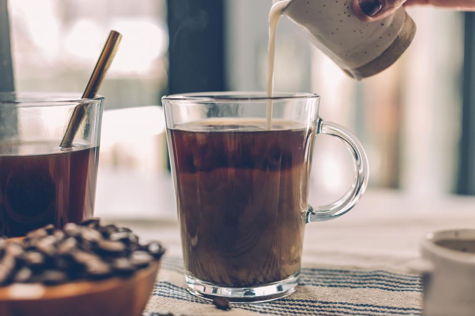 Free Image of Creamy milk pouring into coffee cup 