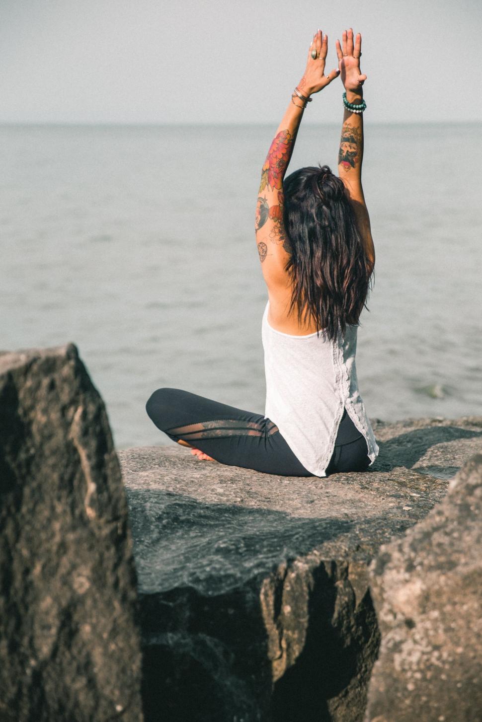 Free Image of Woman meditating peacefully on rocky shore 