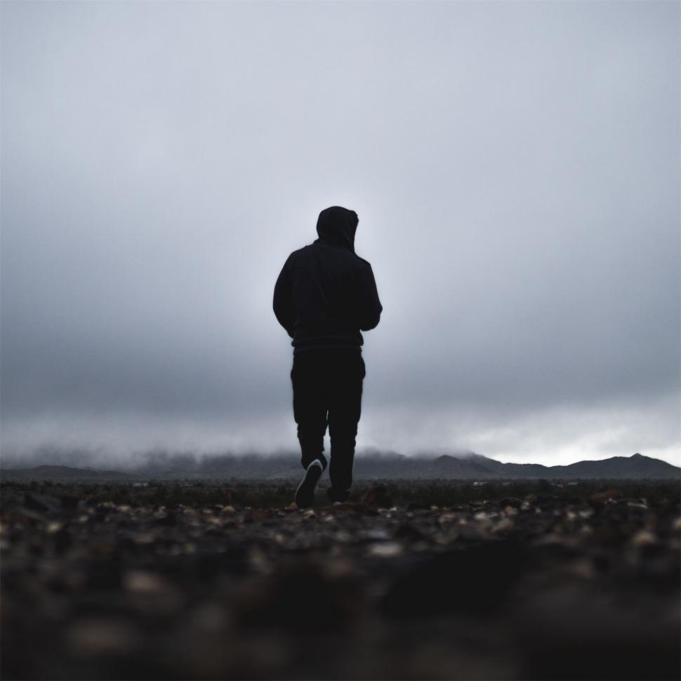 Free Image of Silhouetted figure walking in misty terrain 