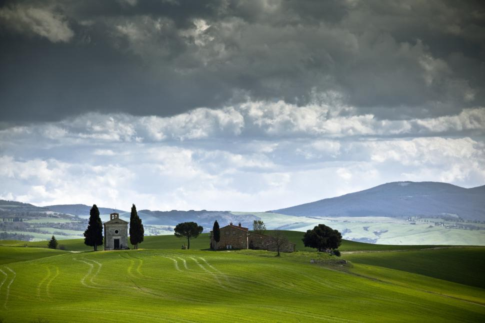 Free Image of A green rolling hills with a building and trees 