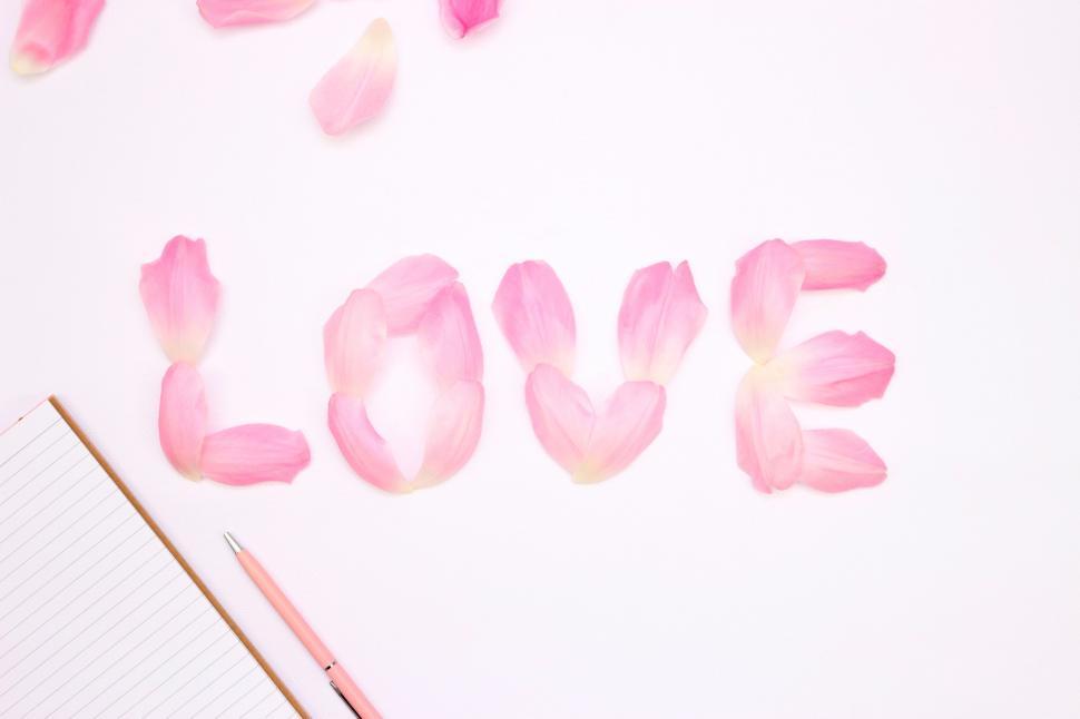 Free Image of Petals arranged to spell LOVE with notebook 