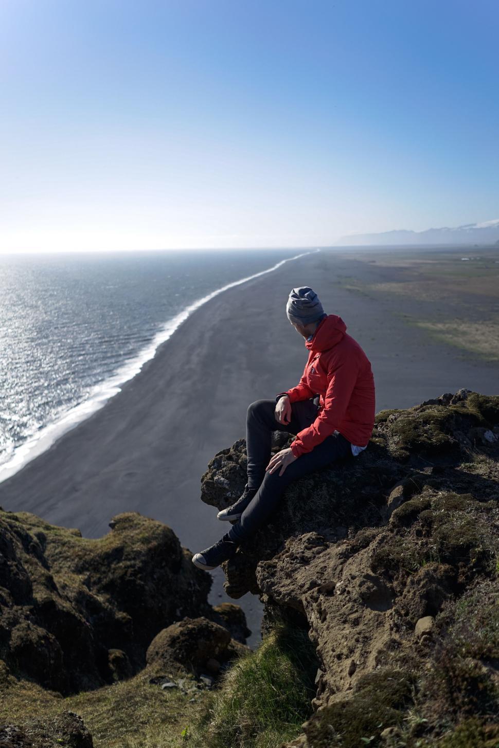 Free Image of Person overlooking vast black sand beach 