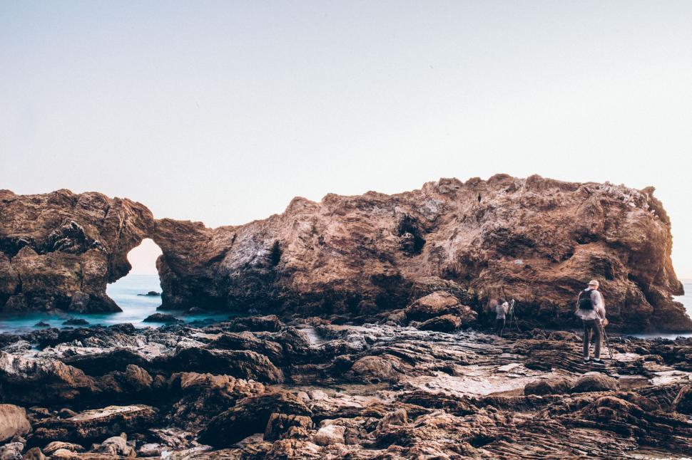 Free Image of Rocky beach with natural arch and people 