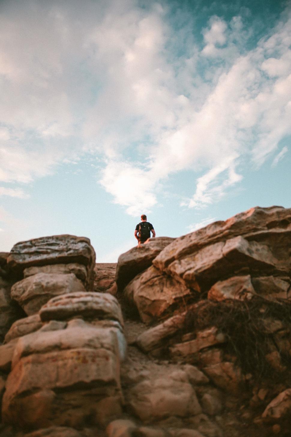 Free Image of Solitary person sitting on rocky cliff at sunset 
