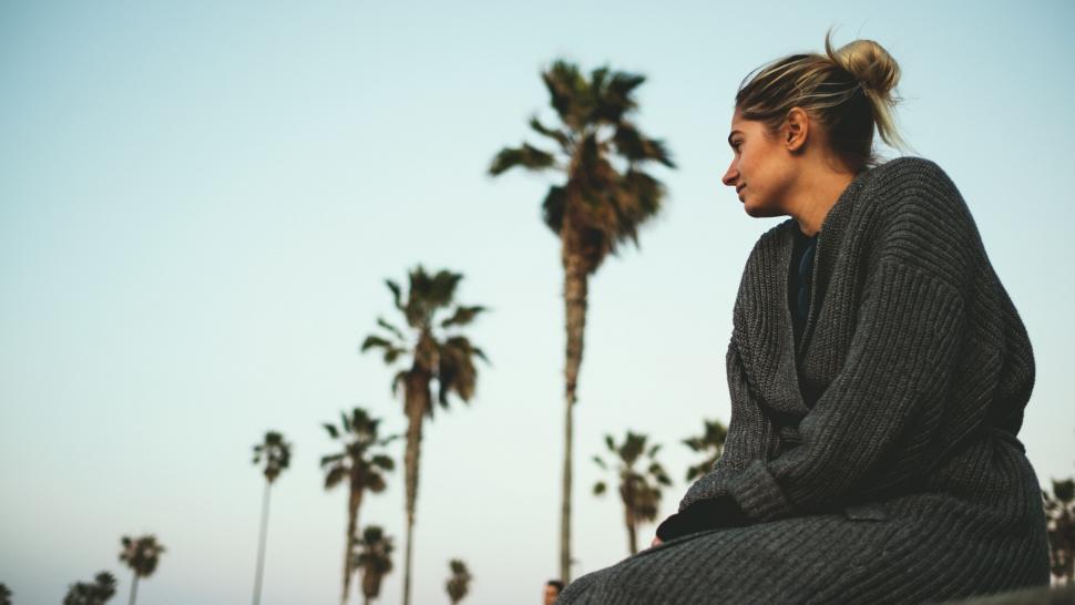 Free Image of Woman sitting by palm trees 