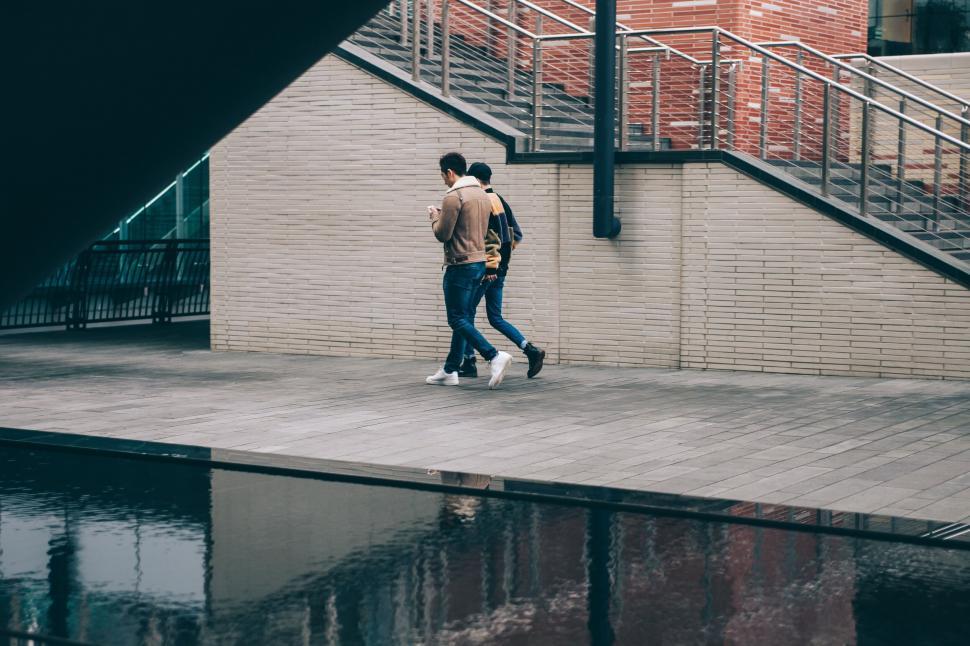 Free Image of Man climbing stairs near a reflective water body 