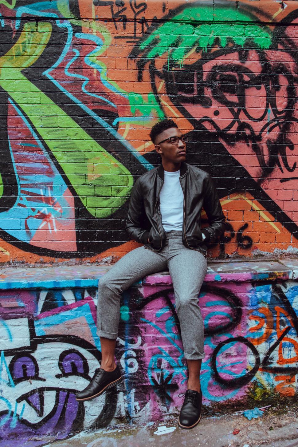 Free Image of Man posing against graffiti wall 