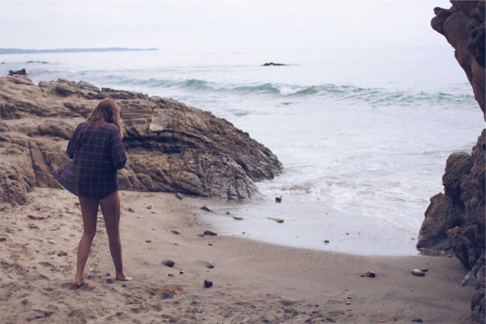 Free Image of Woman stands facing ocean waves at beach 
