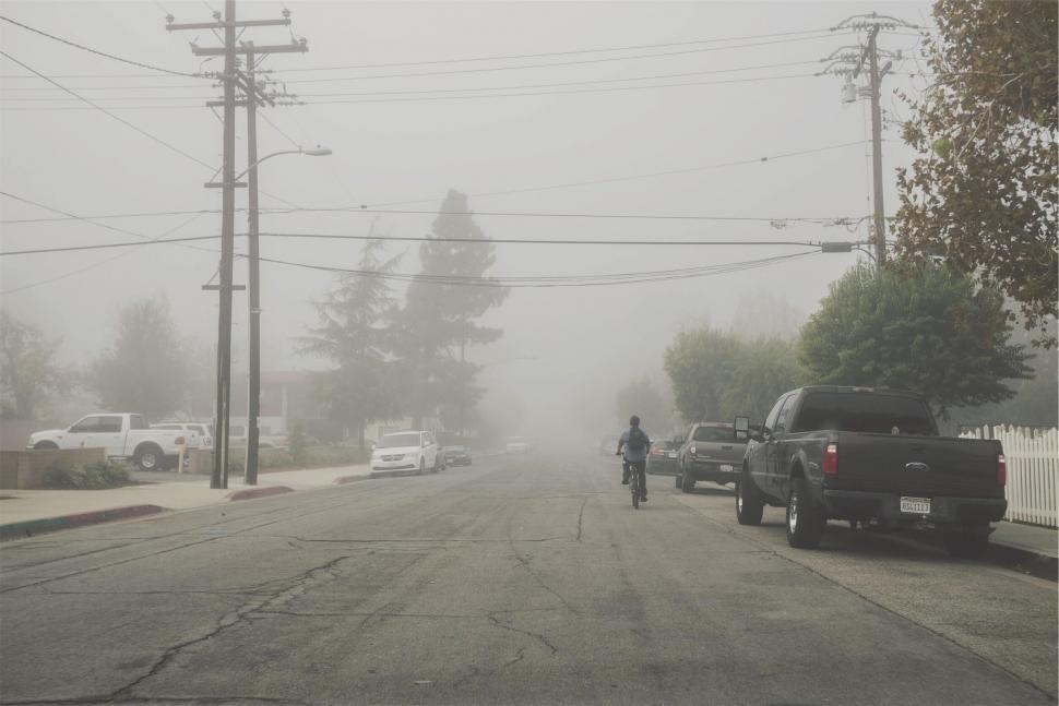 Free Image of Foggy suburban street with cyclist and cars 