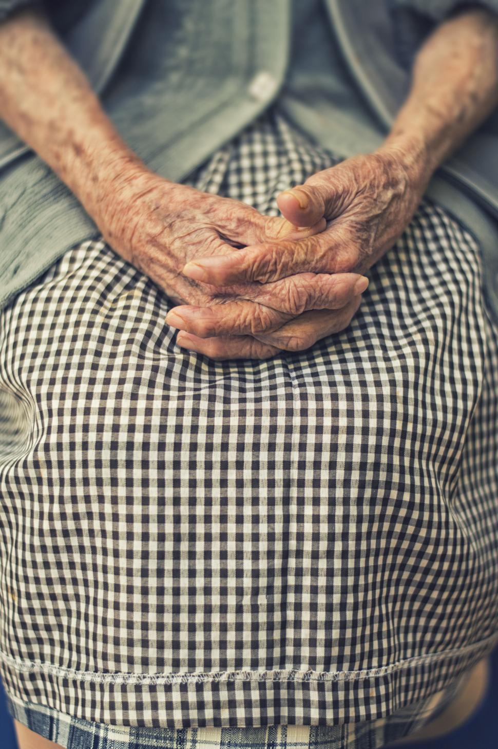 Free Image of Elderly hands resting on a checkered back 