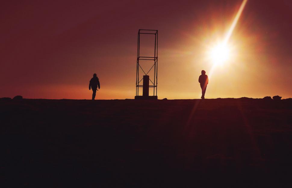 Free Image of Silhouette of two people by a mountain structure 
