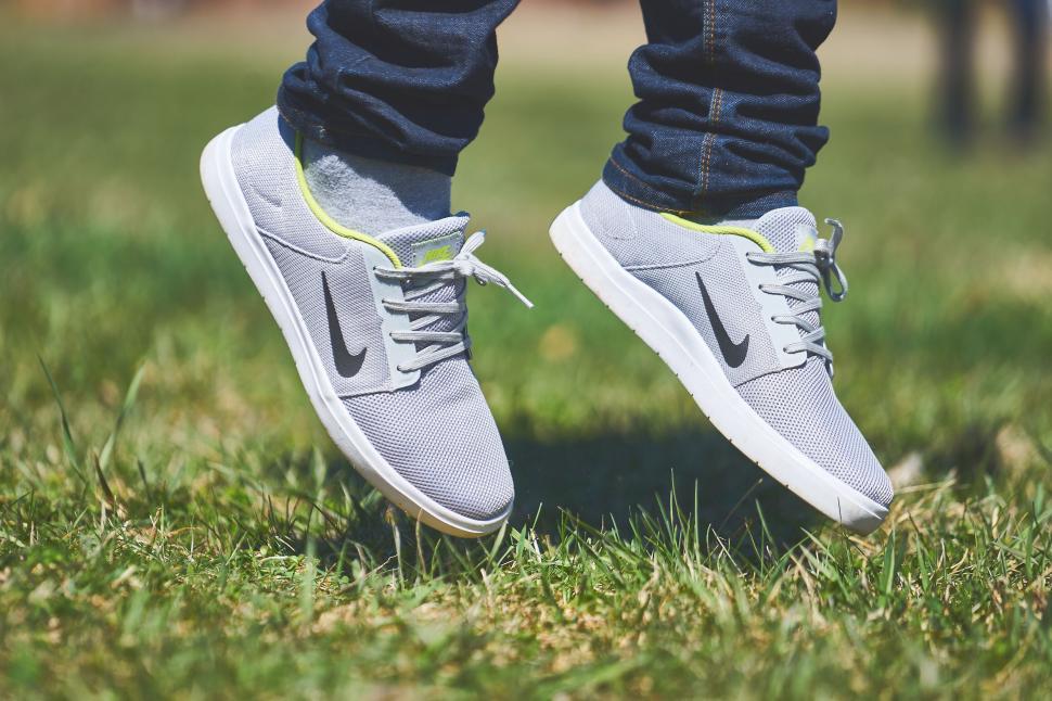 Free Image of Person tying Nike sneakers on grass 
