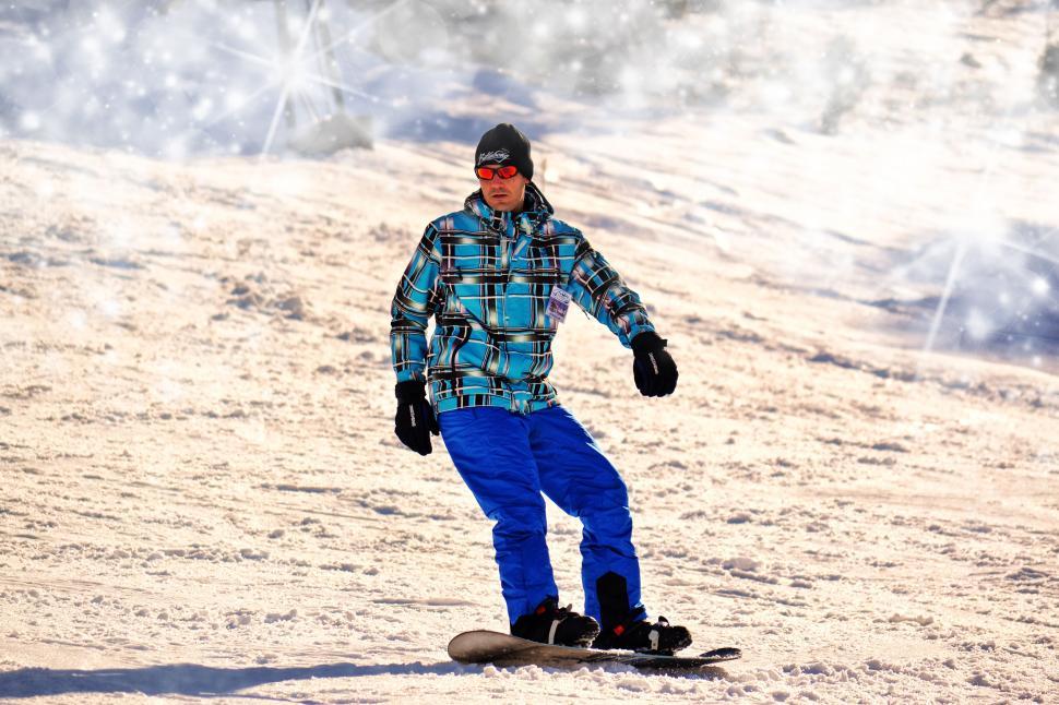 Free Image of Snowboarder sliding down a snowy hill 