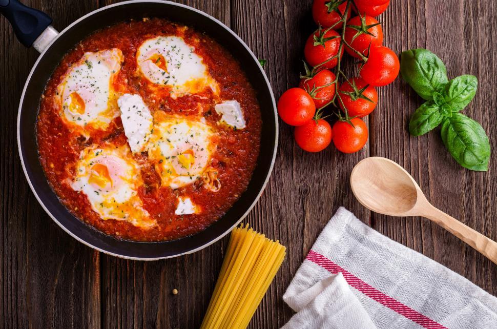 Free Image of Shakshuka in a pan with ingredients around 