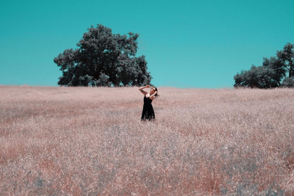 Free Image of Woman in field enjoying nature under blue sky 