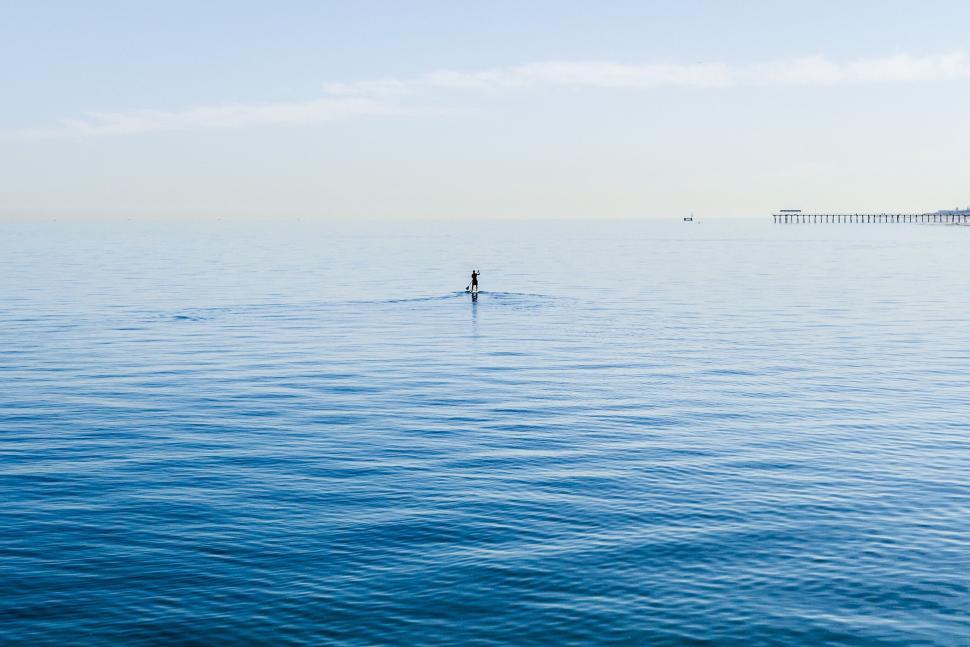 Free Image of Lone paddleboarder on calm blue sea 