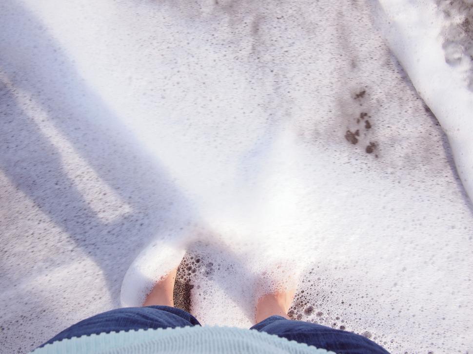 Free Image of Feet standing at the ocean s edge on sand 