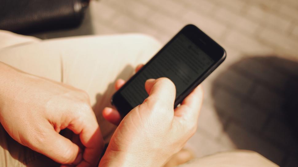 Free Image of Person holding smartphone reading text 