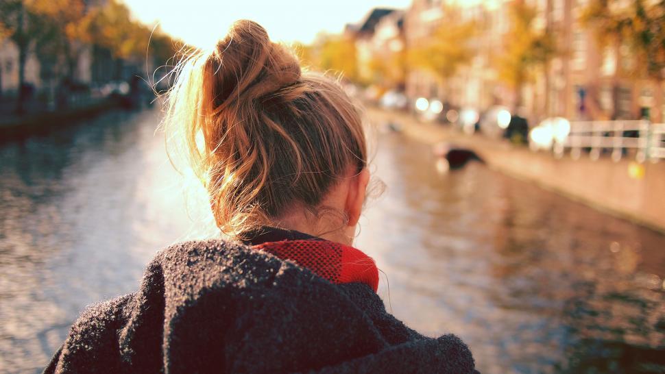 Free Image of Woman gazing canal in autumn light rear view 