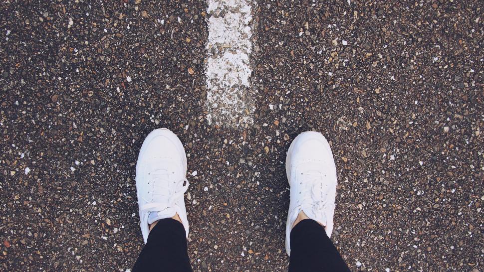 Free Image of Top view of feet on gravel road by white line 