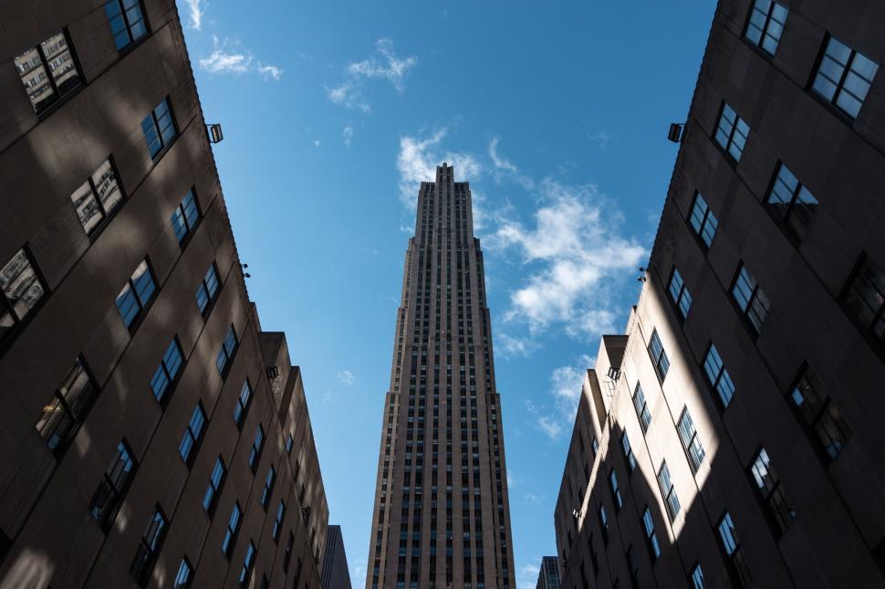 Free Image of Skyscraper rising between two buildings under blue sky 