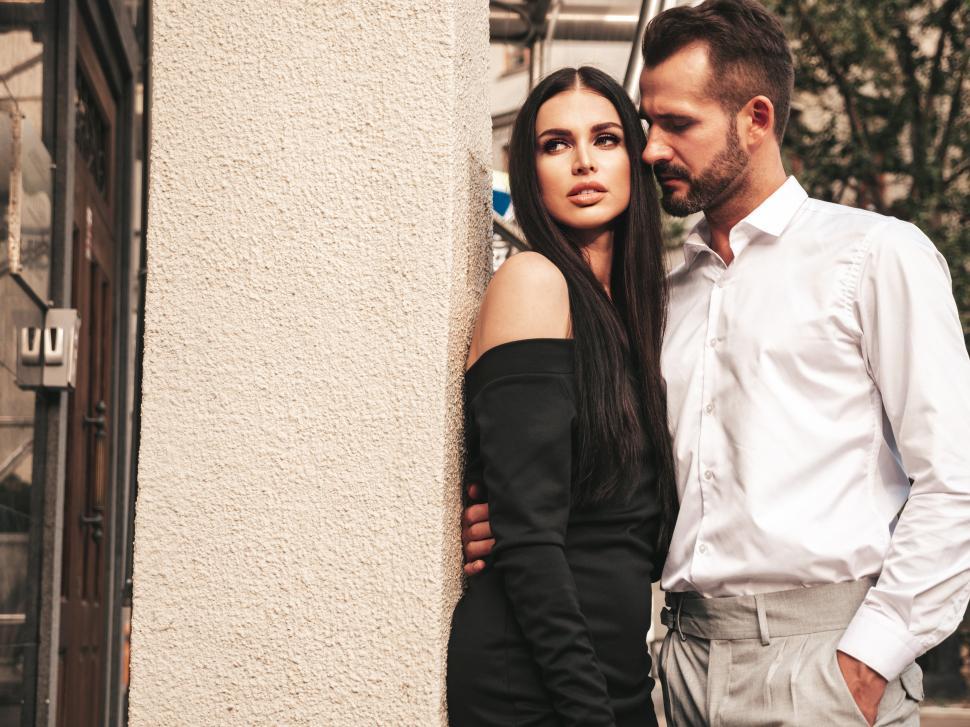Free Image of A man and woman leaning against a wall 