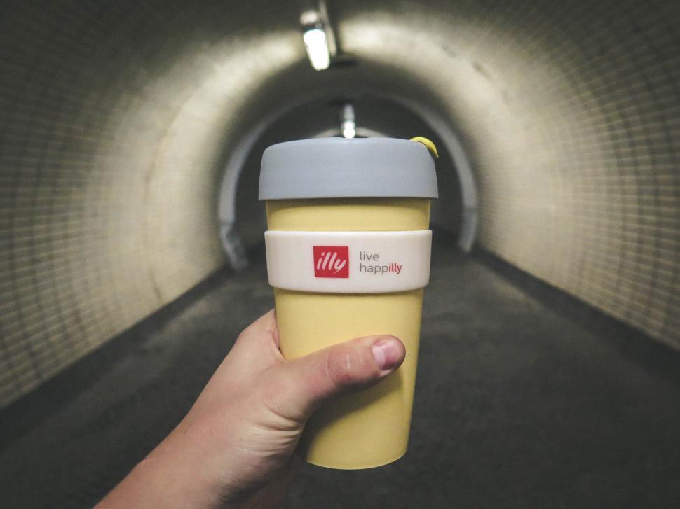 Free Image of Hand holding a yellow Illy cup in a tunnel 