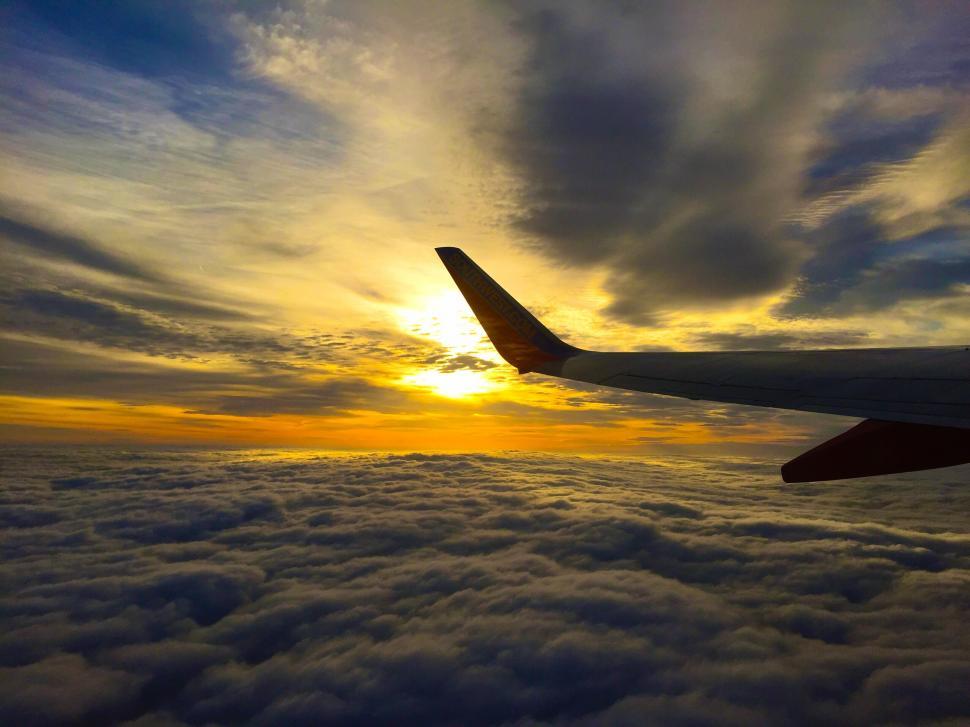 Free Image of Airplane wing over golden cloudscape 