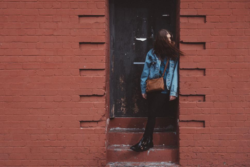 Free Image of Woman sitting in front of a brick wall 