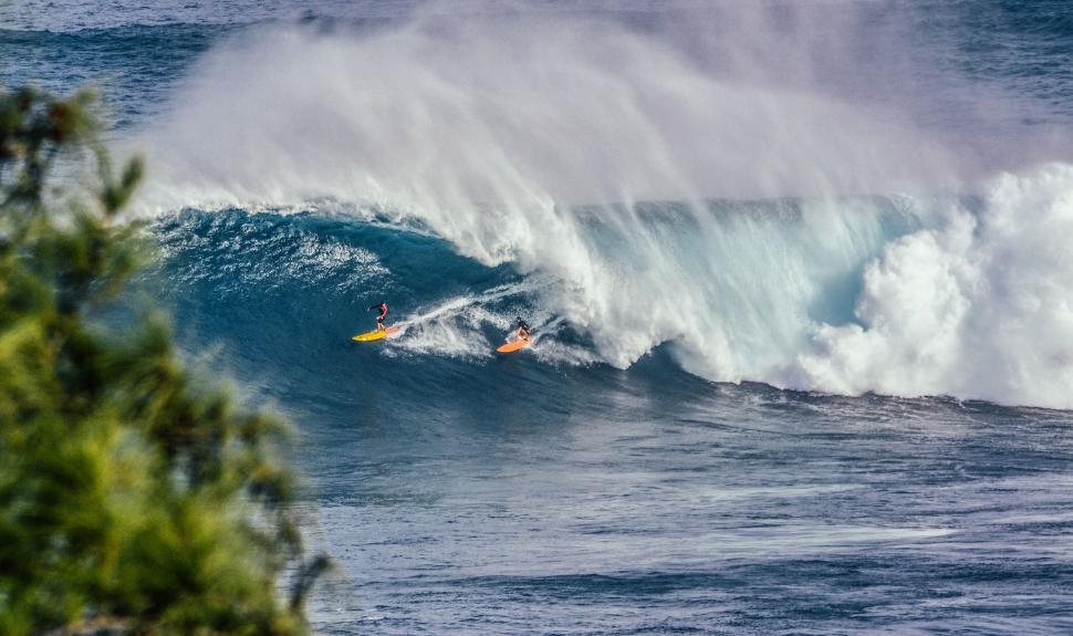 Free Image of Surfers riding a massive wave together 
