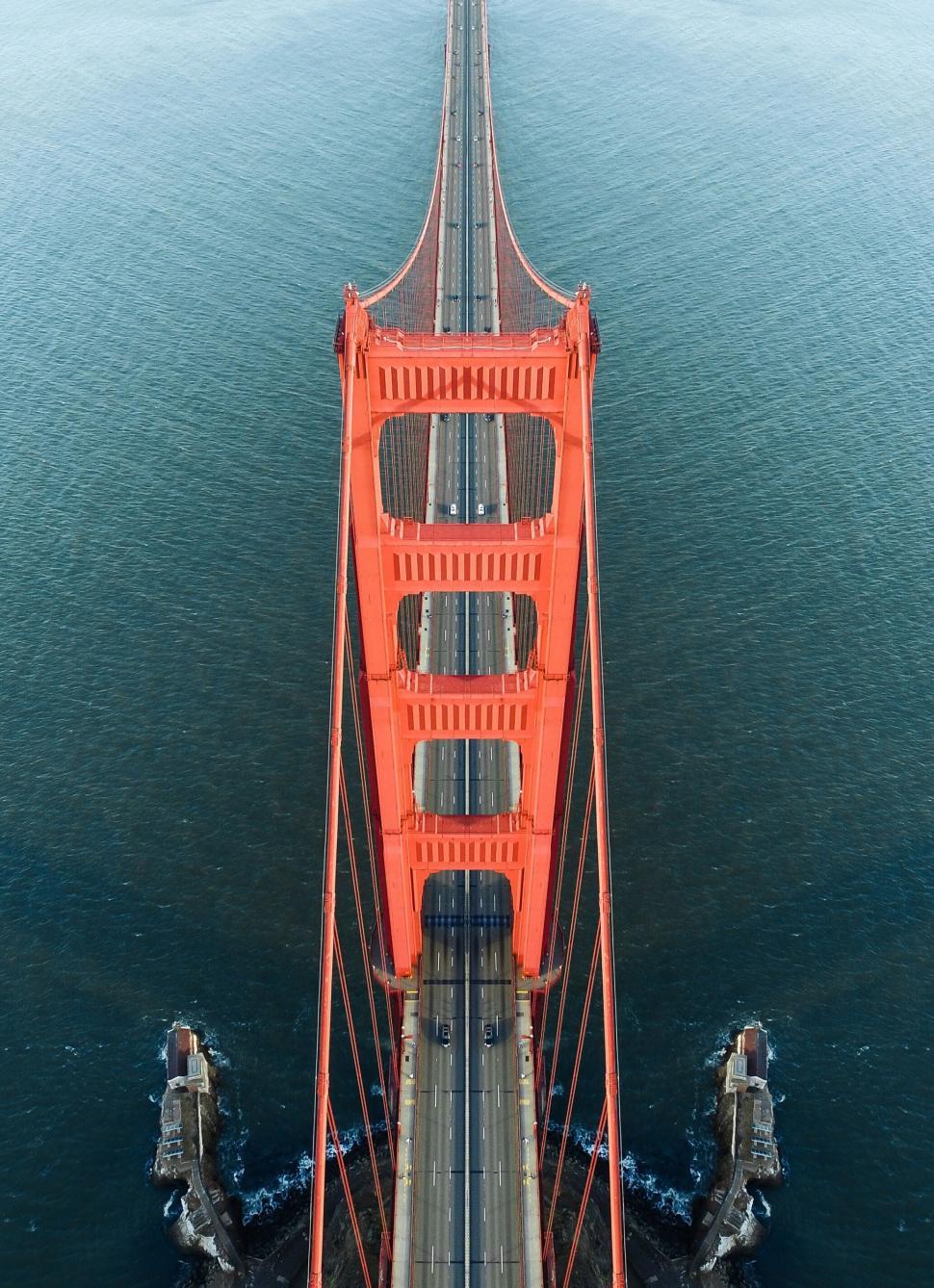 Free Image of Close-up of orange suspension bridge tower against blue water 