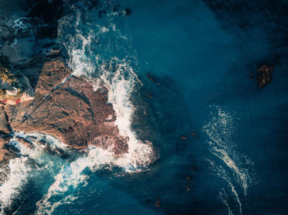 Free Image of Ocean waves hitting rocky cliffs from above 