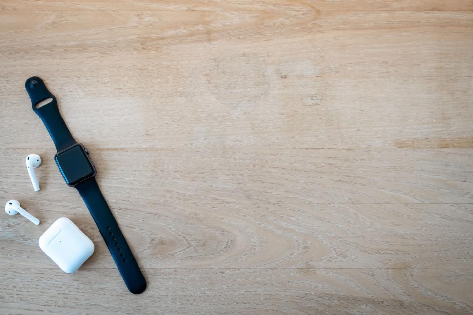 Free Image of Smartwatch and earbuds on wooden background 