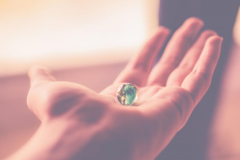 Free Image of Open palm holding a marble with soft light 