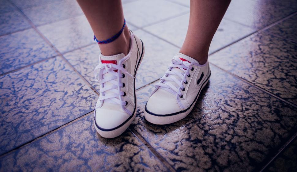 Free Image of Close-up of white sneakers on tiled floor 