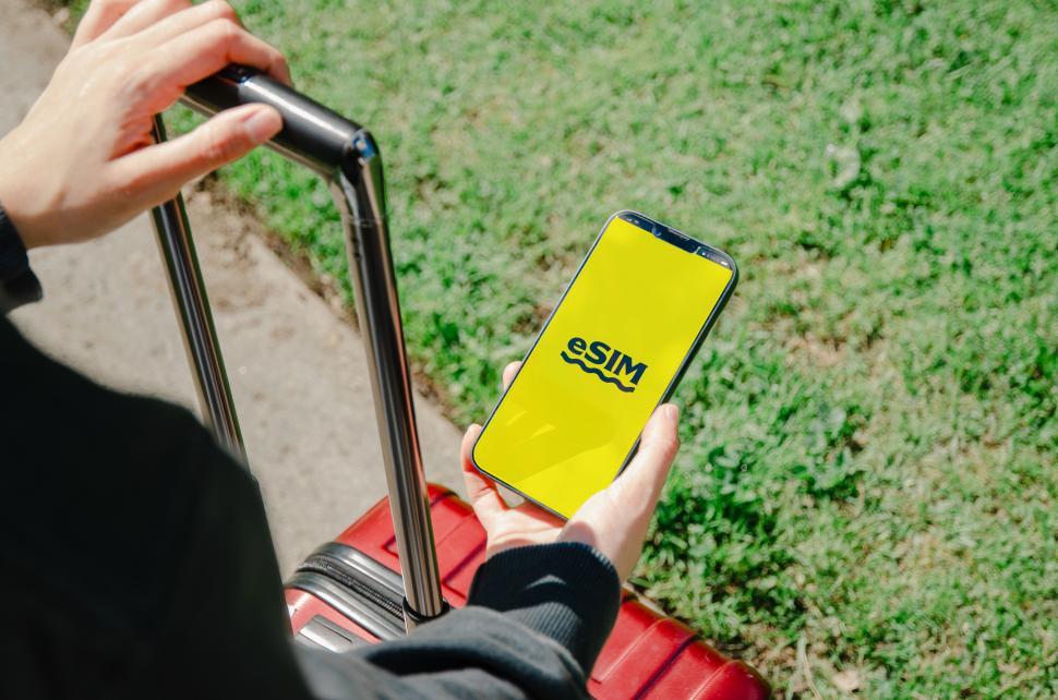 Free Image of A photo displaying a U.S. passport and a smartphone with an eSIM logo, symbolizing modern travel technology  