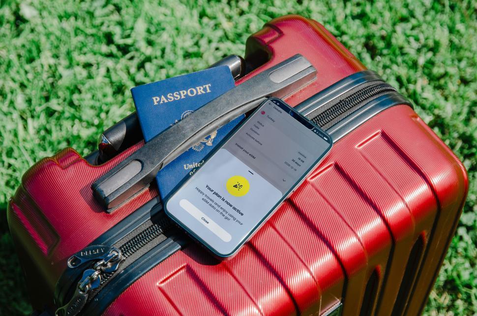 Free Image of A hand holding both a passport and a phone with an eSIM, indicating the modern necessities for international travel  
