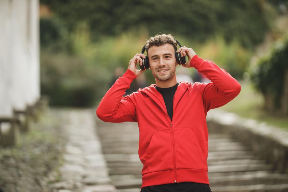 Free Image of Man enjoying music outdoors in sporty red hoodie 