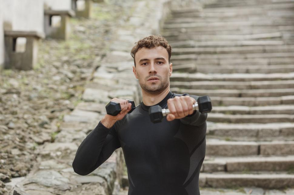 Free Image of Young man lifting weights outdoors 