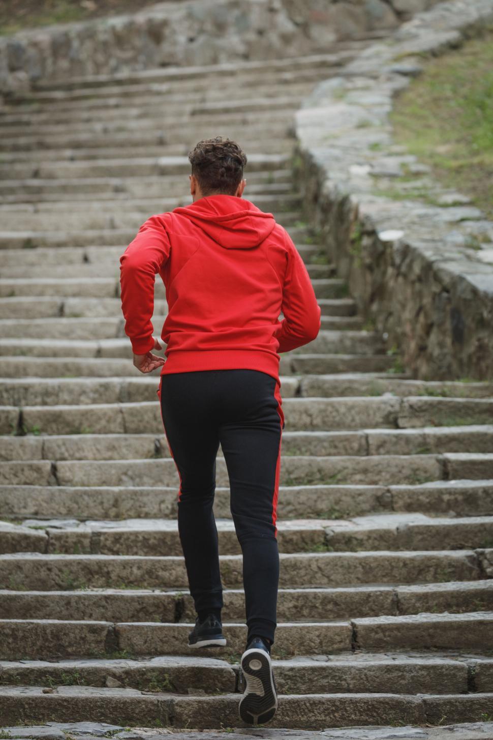Free Image of Woman climbing stairs in red hoodie outdoors 