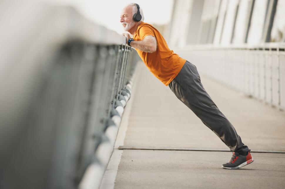Free Image of Man stretching on a bridge railing 