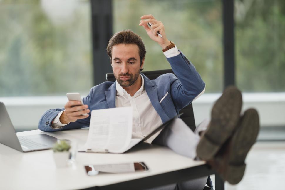 Free Image of Businessman relaxed with feet up and phone 