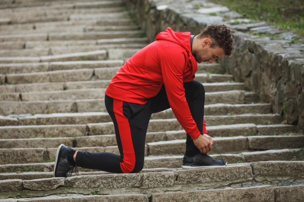 Free Image of Man tying shoelaces on stone steps outdoors 