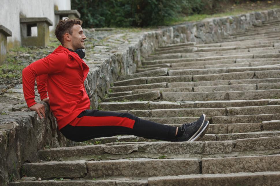 Free Image of Athlete resting on ancient stone steps 