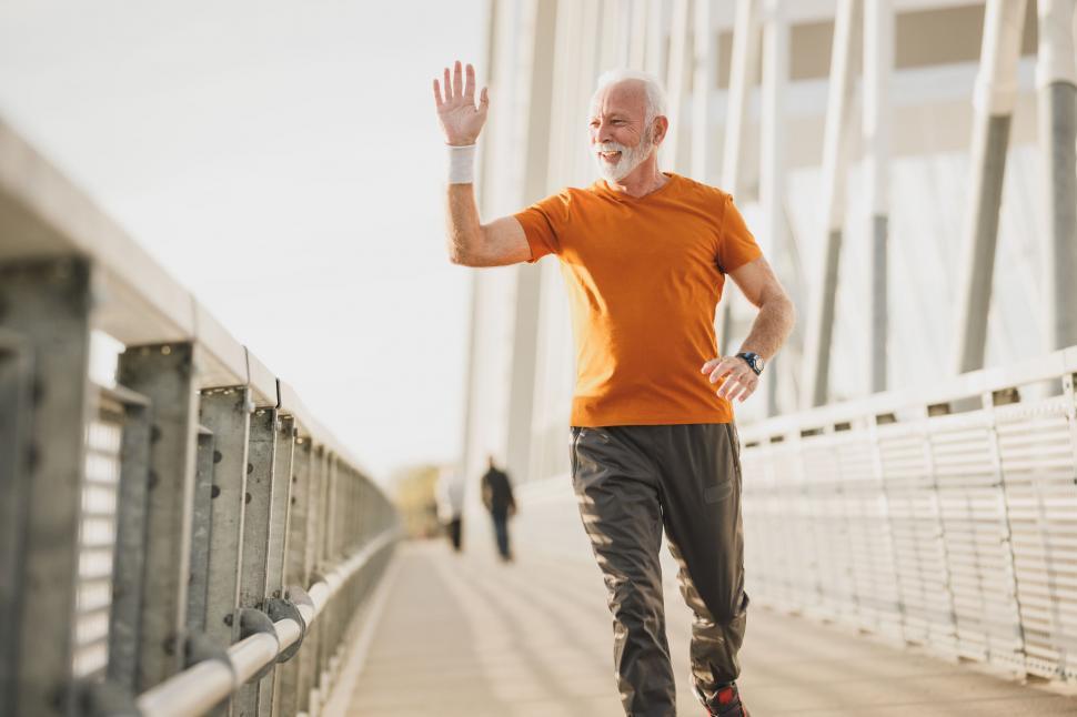 Free Image of Runner waving hello on a bridge 