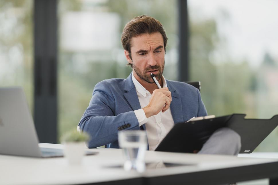 Free Image of Businessman examining documents thoughtfully 