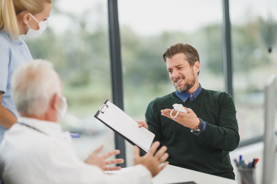 Free Image of Patient sneezing during consultation with doctor 