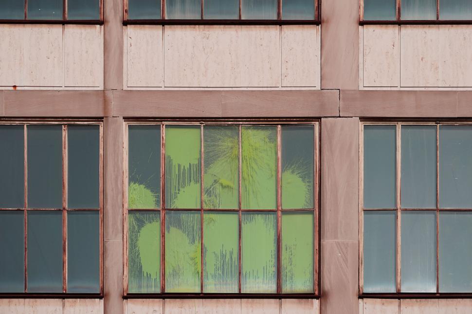 Free Image of Green foliage reflecting on a building window 