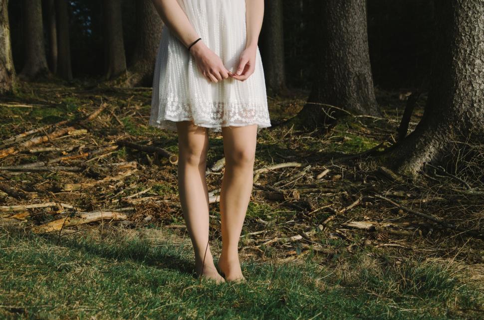Free Image of Woman in white dress standing in woods 