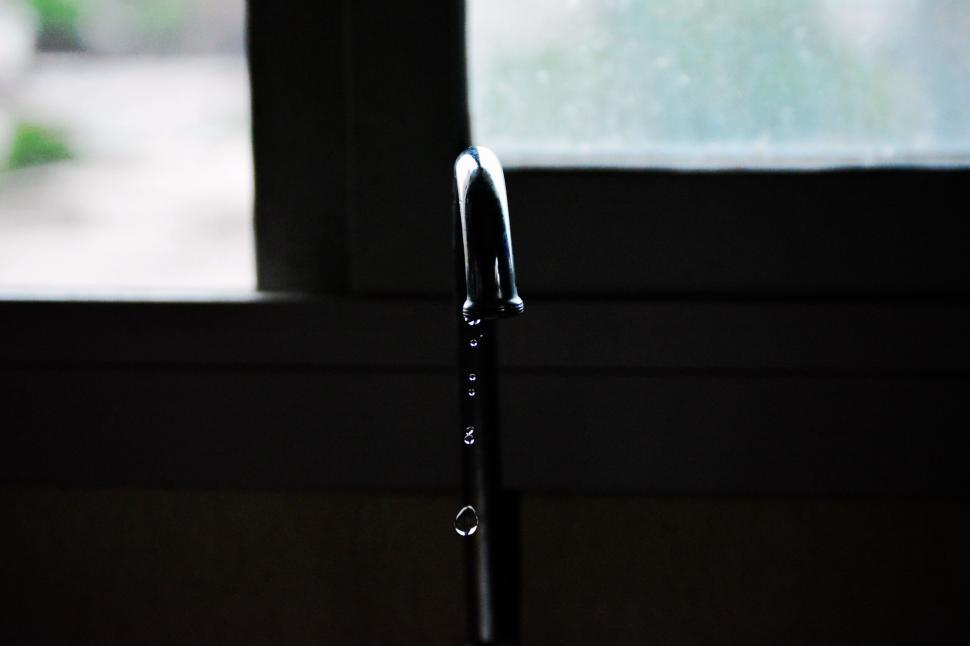 Free Image of Water faucet dripping against dim light 